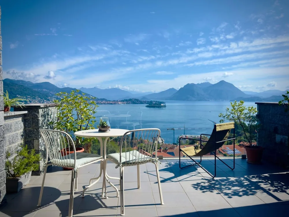 The private terrace with a dining table, chairs and a sun lounger above Lake Maggiore
