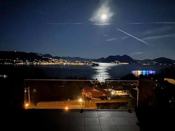 Lake Maggiore and the far shore lit up at night, seen from a terrace under the moon